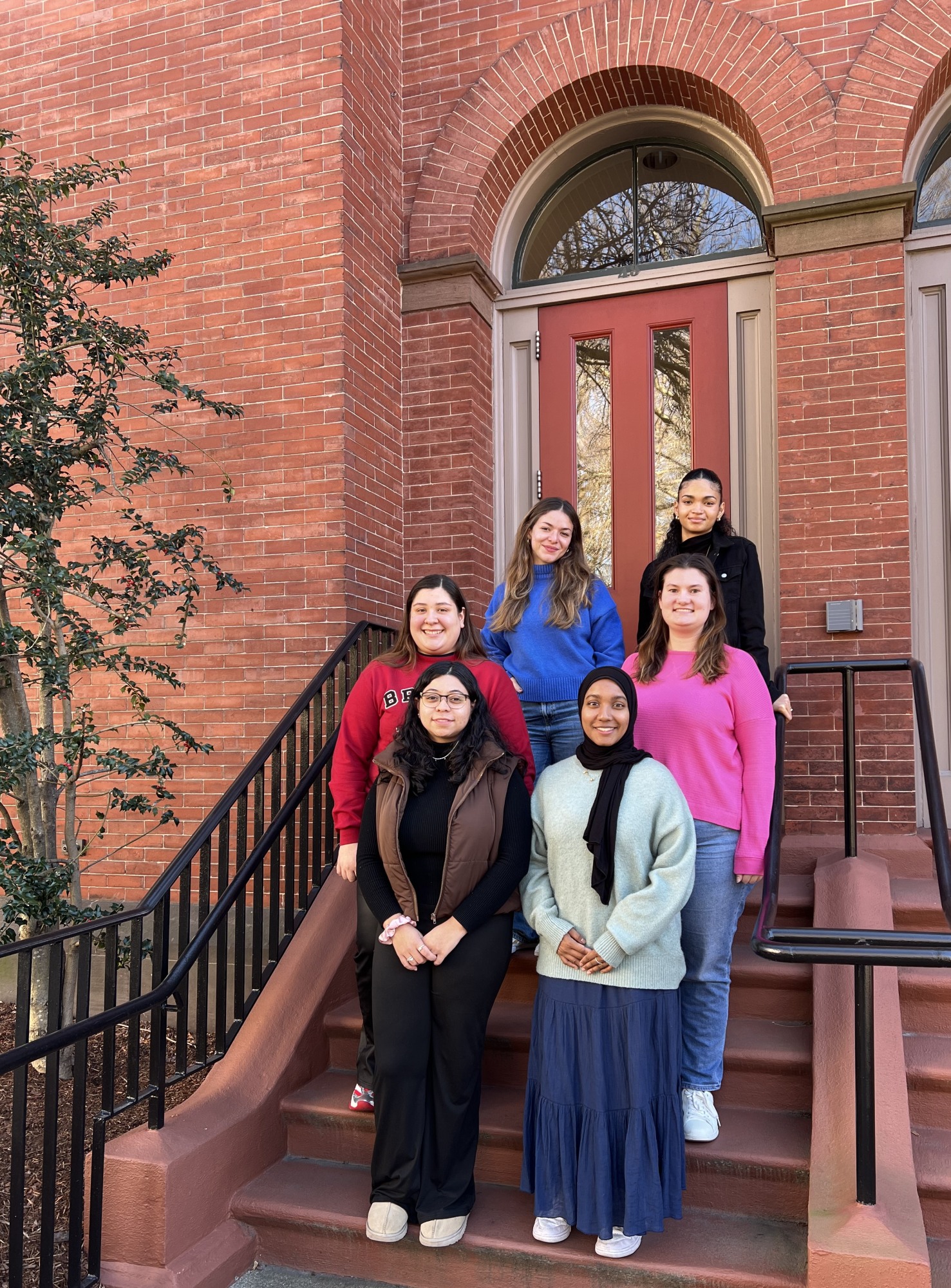 Group of students standing on the front steps of a brick building